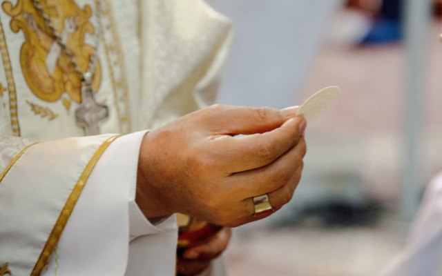 A Priest distributing the Holy host during first communion.